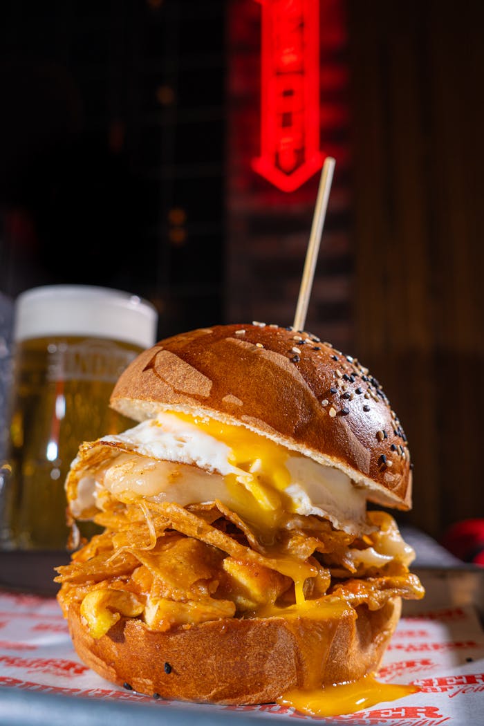 Delicious gourmet cheeseburger topped with a fried egg and crispy potato chips served in a rustic setting.