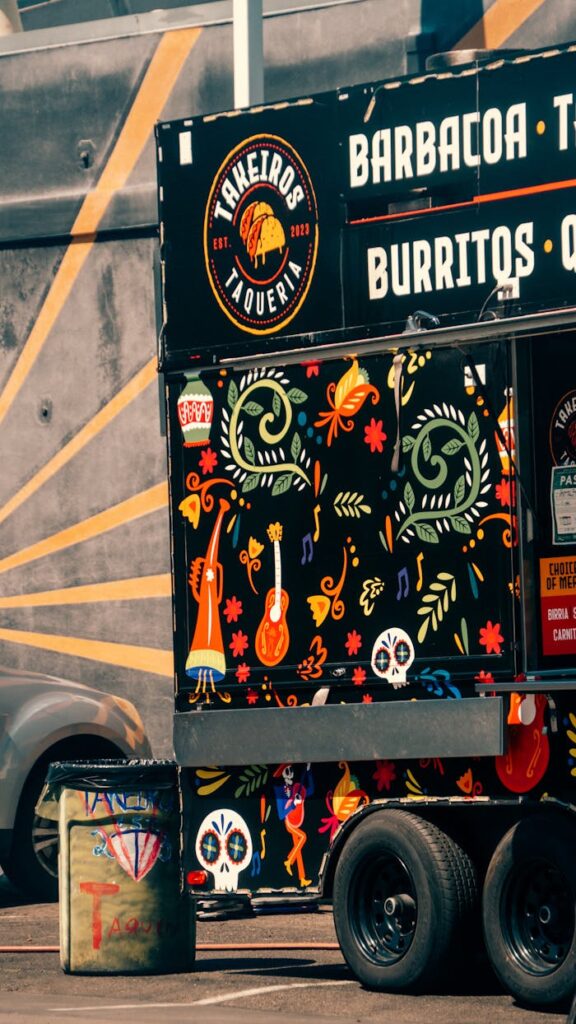 Colorful Mexican food truck with vibrant artwork and bold textures in a sunny urban setting.